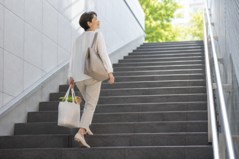 A woman walking up stairs while carrying groceries as part of her daily routine