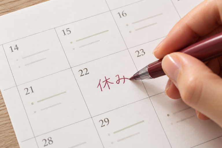 スケジュール帳の予定欄に、赤いペンで「休み」と書き込む手元